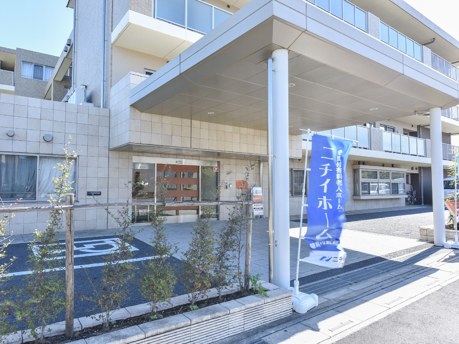 エントランスのすぐ隣には車いす専用の駐車場が完備されている。また、植え込みには草木が植えられていて美しい。