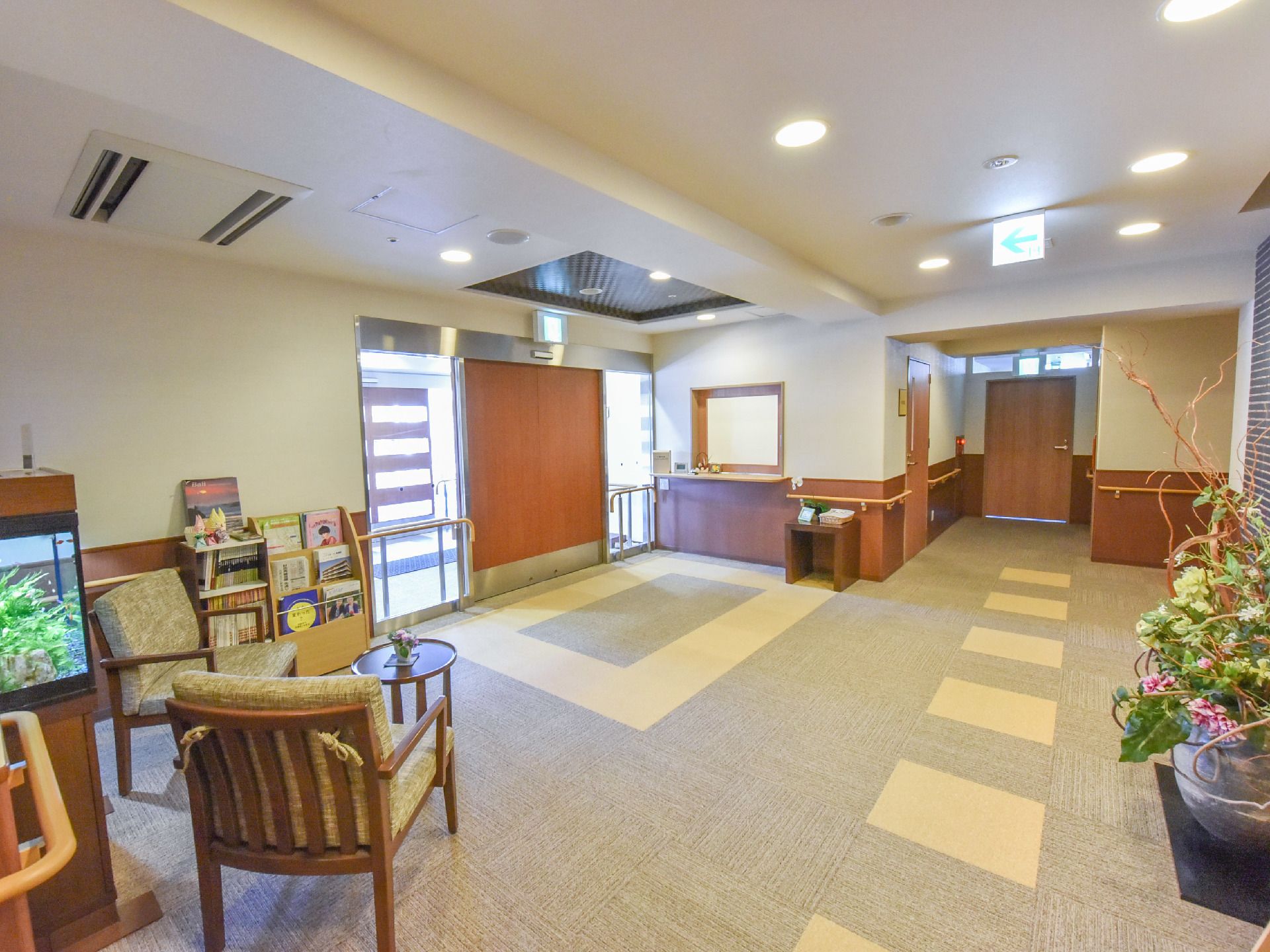 館内入口の自動ドアをあけると、カーペットを敷いた空間が広がっており、本を読んで過ごせるテーブルと椅子などが設置されている。