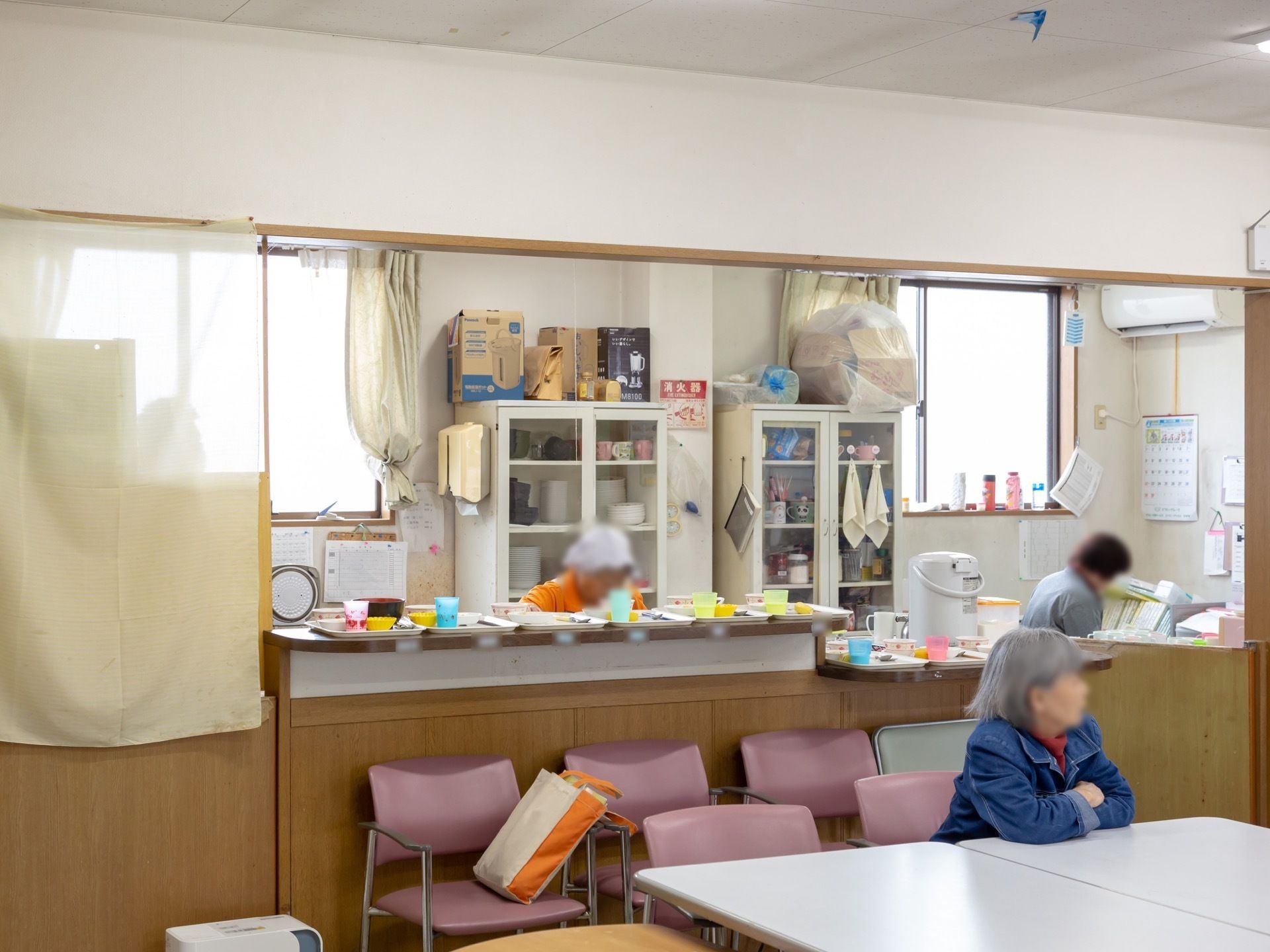 食堂は調理場と隣接しており、調理の様子が見えるようになっている。カウンターにトレーが置かれ、食事の準備がされている。