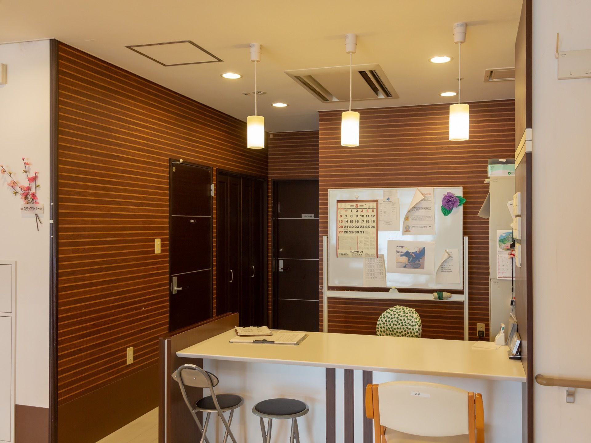 エントランスにはハイカウンターがあり、入居者様とスタッフが交流できる受付がある。ホワイトボードにカレンダーなどが貼られている。