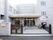 施設は白のタイル張りの3階建ての建物。入り口には門があり奥に入口の自動ドアが見える。駐車場も備えている。
