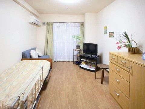 柵付きの介護用ベッドが置かれている。ソファの前にはテレビがあり、リラックスして鑑賞できる。エアコンが設置されており、常に快適である。