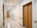 木目の扉と手すりが目立つ白い廊下。一見するとトイレに見えない扉はボタンで開閉してライトで使用を確認できる。