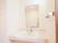白をメインにきれいな洗面台。大きな鏡とタオル掛けが取り付けてある明るい空間。トイレと一緒に設置してある。
