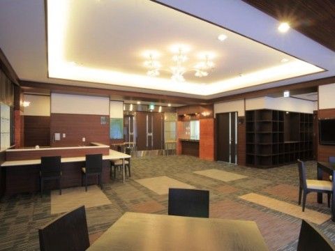 広々としたエントランス。間接照明がつけられているので、落ち着いた雰囲気になっている。テーブルと椅子が並べられている。
