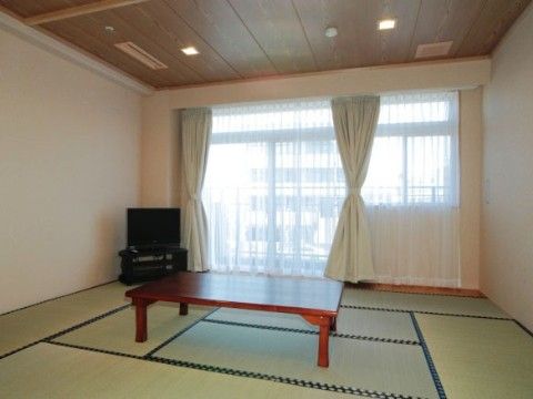 10畳ほどの和室がある。大きな窓にはレースのカーテンがかけられている。茶色いテーブルとテレビも用意されている。