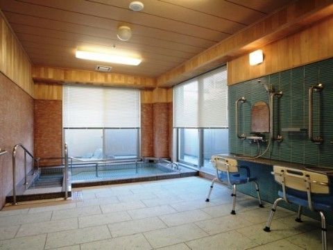 施設には大浴場があり、浴槽は大きい。安全に浴槽に入っていただけるように、手すりが取り付けられている。洗い場にはお風呂の椅子もある。