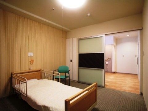 居室の床には茶色いタイルカーペットが敷かれており、滑らないようになっている。ベッドの上側の壁には呼び出しボタンが設置されている。