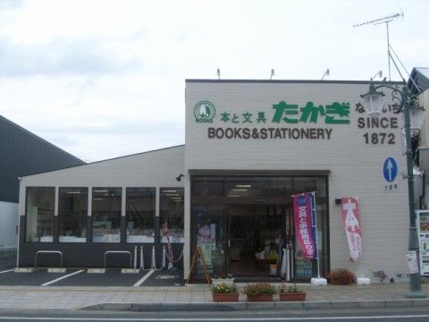 道路に面した場所に本と文具を取り扱っているお店がある。外壁は白色で、緑色の立体文字でお店の名前が書かれている。