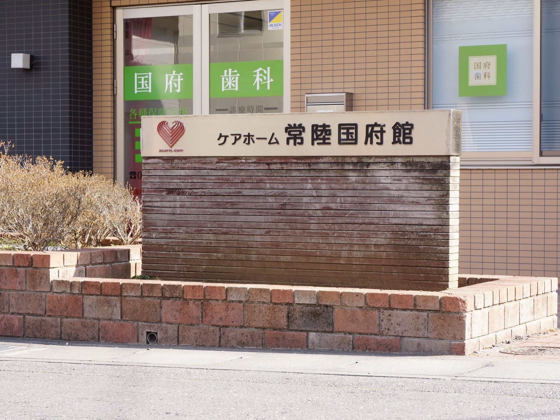 花壇の横には施設の表示板が設置されており黒文字で大きな印字になっているため、道路からの確認が容易である。