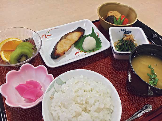焼き魚と野菜の煮物やご飯と味噌汁とフルーツのデザートのセット
