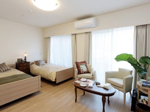 二人部屋はゆとりのある間取りになっており、エアコンやベッド、家具が備わっている。自然光が差し込む大きな窓が設けられている。