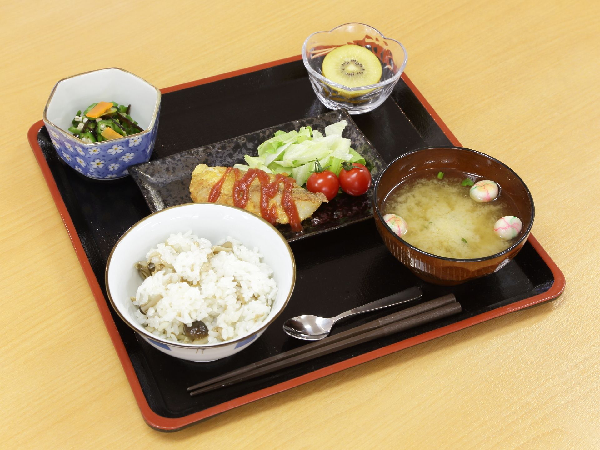 栄養管理をされている献立が食堂で提供される。メインの他、ご飯、味噌汁、小鉢、果物がお盆の中に配置されている。