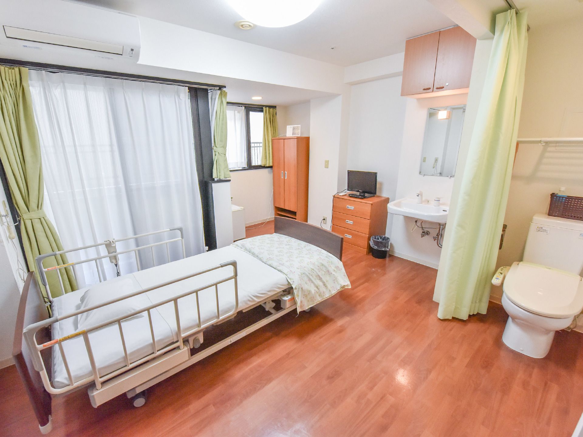 ベッドを置いてもゆとりがあり、収納も豊富。カーテンで仕切られたトイレスペース。エアコンが設置されている。
