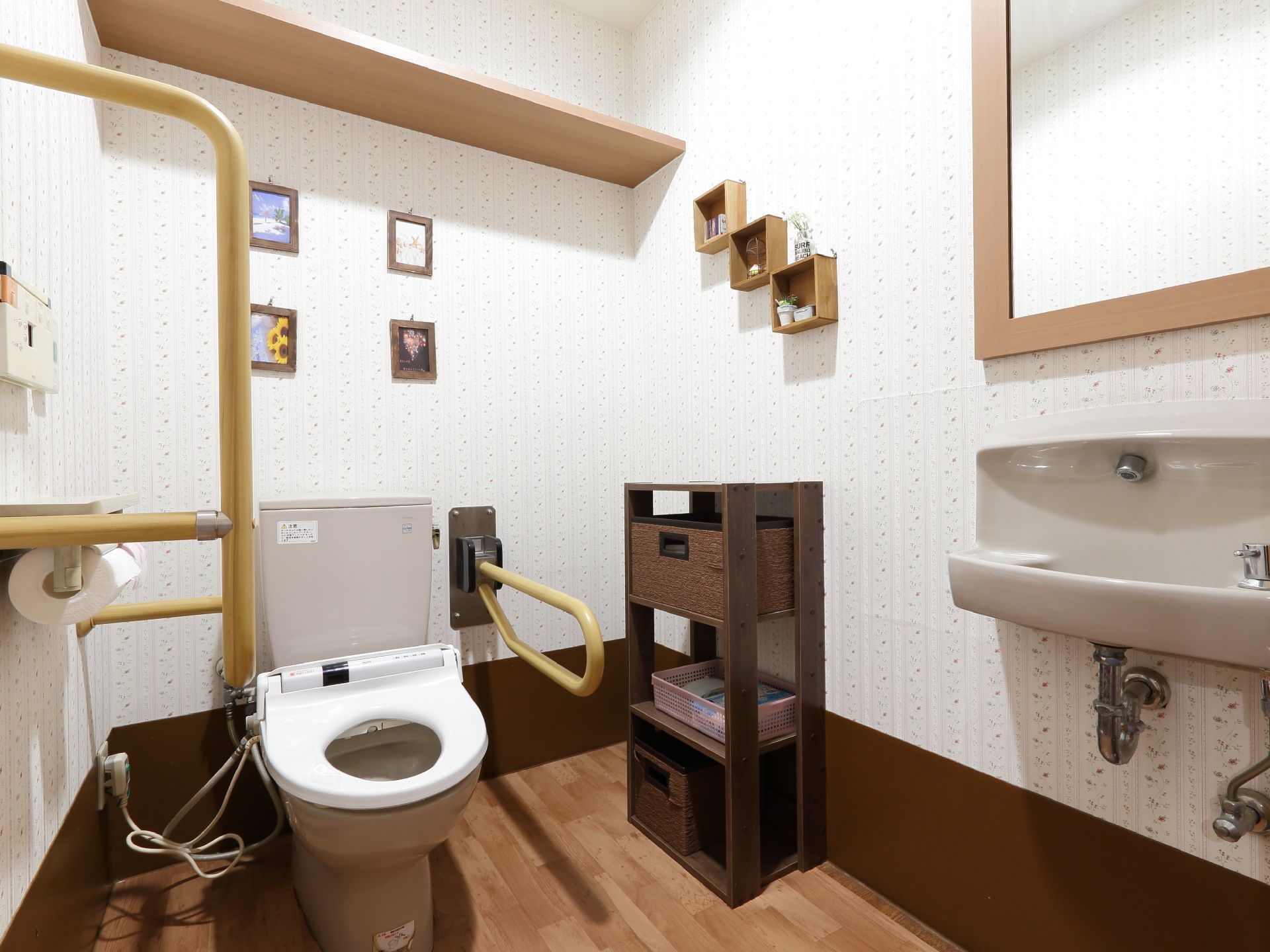 トイレの内装はダークブラウン系である。壁には装飾が施されている。バリアフリーの手すりも設けられている。