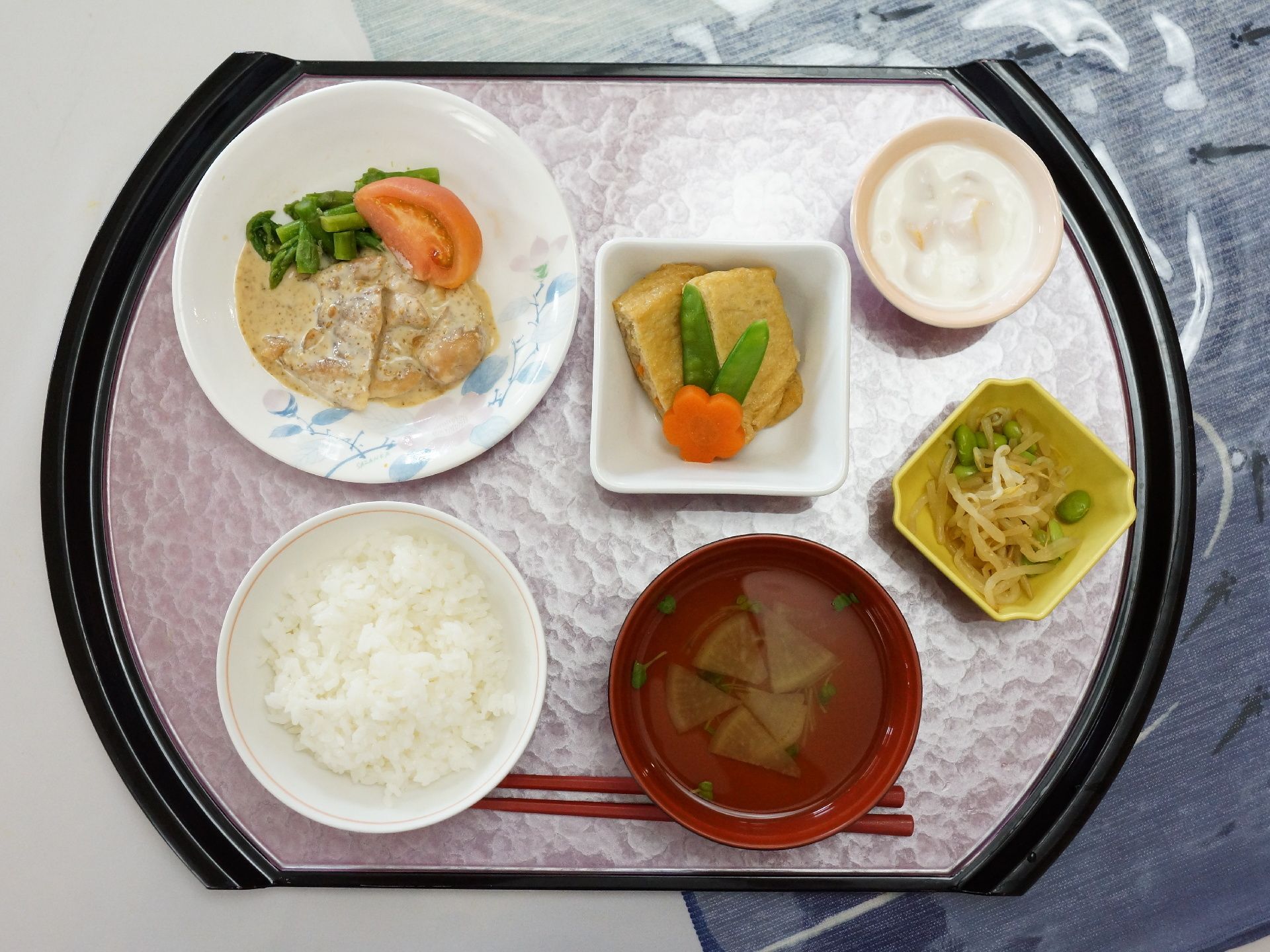 施設で入居者に提供される食事。変わった形状の膳の上に白米を中心とした和食メニューが乗せられ、箸が付属している。