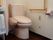 トイレには温水洗浄便座が備えられている。壁には縦横の手すりが設置されており、その下には呼び出しボタンが備えられている。