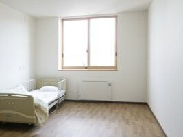 フローリングの部屋には大きな窓があり、寝具付きベッドやパネルヒーターがある。