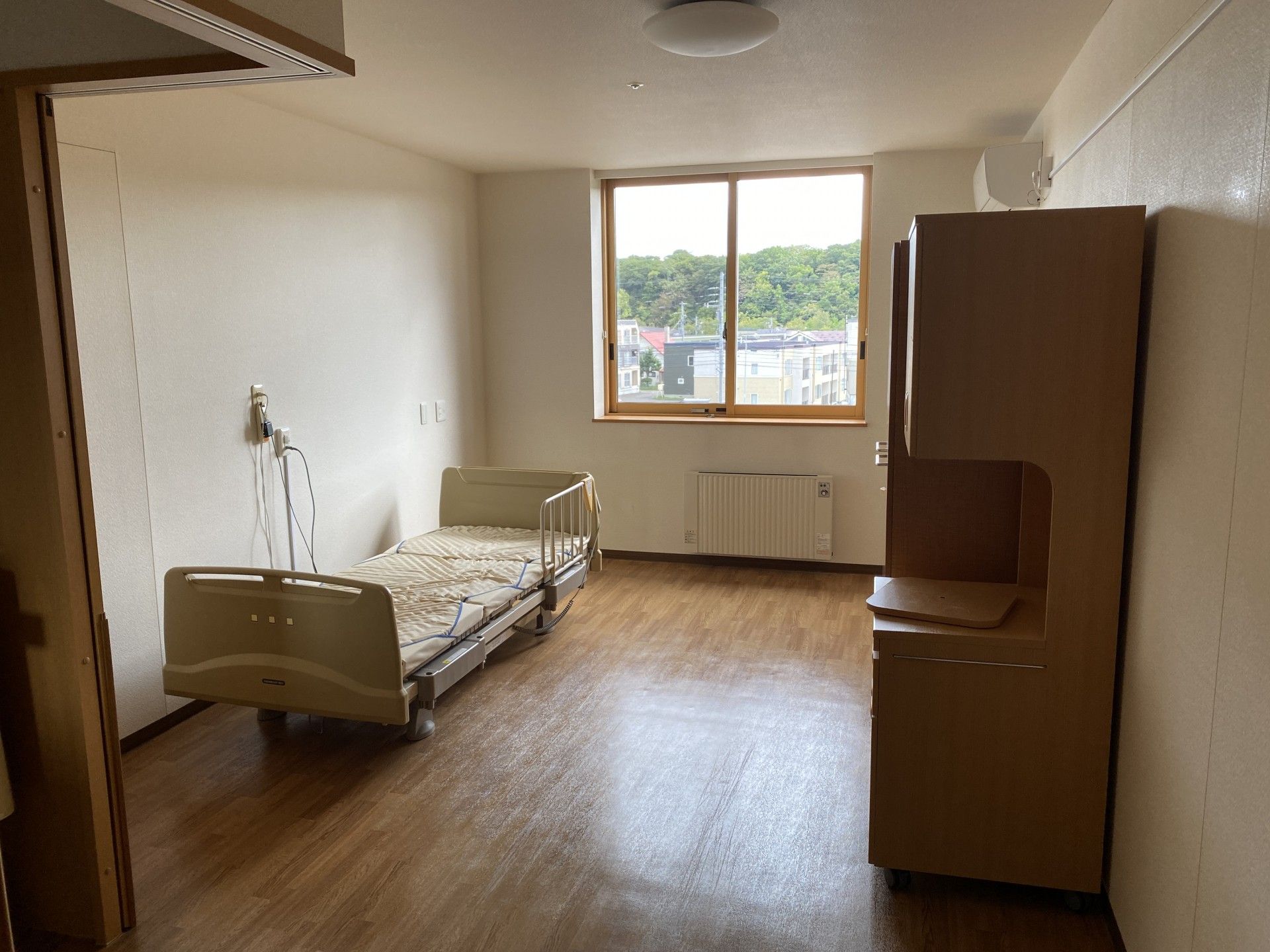 大きな窓が付いた部屋には寝具付きのベッドやパネルヒーターが設置されている。