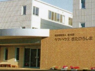 ベージュとブラウンが基調の落ち着いた雰囲気の建物である。建物の周りには花のプランターが置かれており、華やかである。
