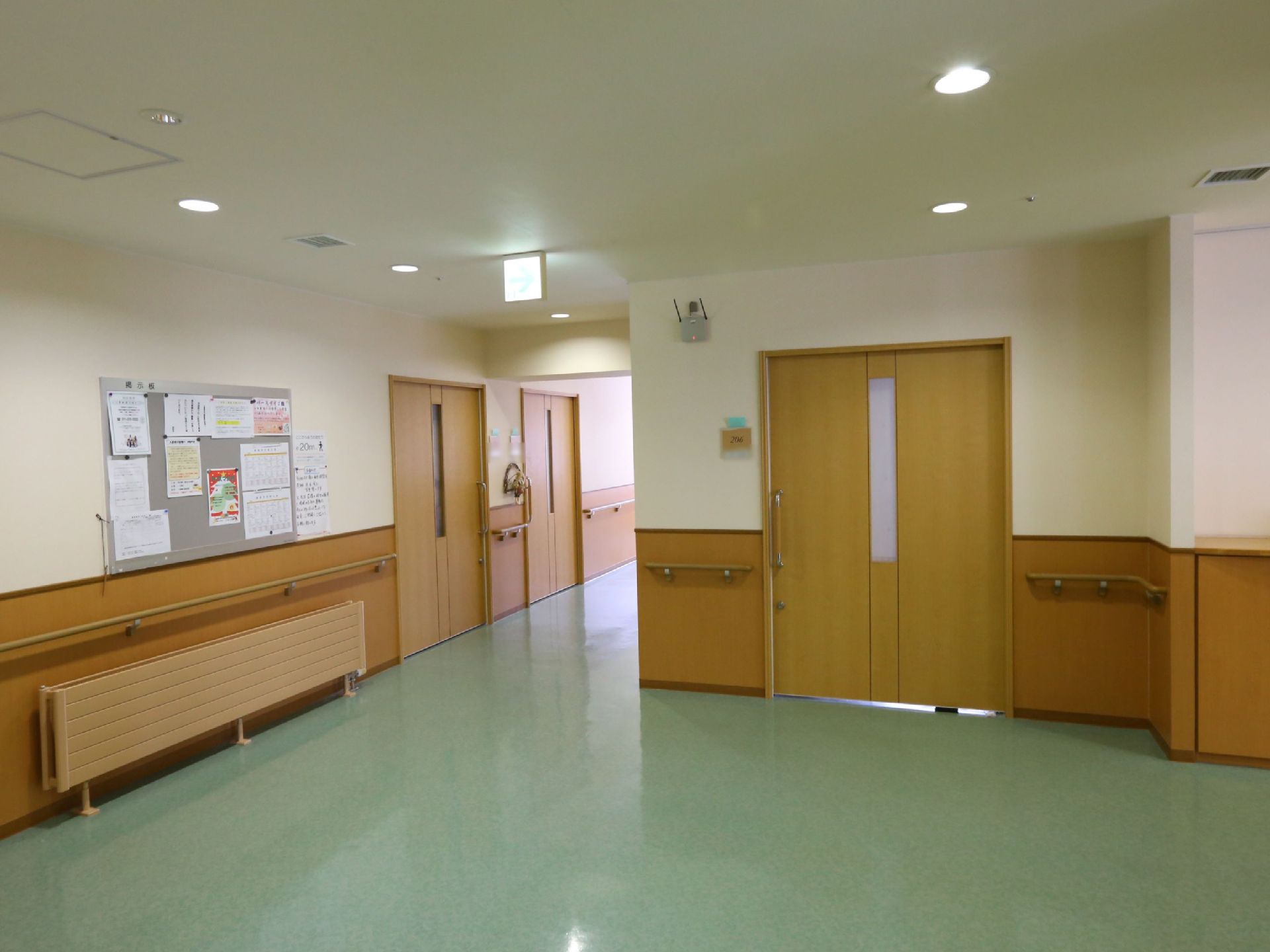 居室前の廊下は幅が広くとってある。白い壁に木目調の腰板を採用しており、連続して手すりが設置されている。