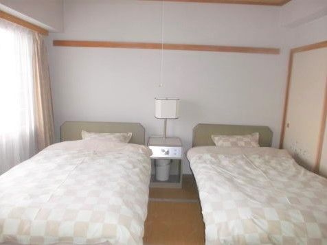 ベッドが二つ並べられた広い部屋。押し入れタイプの収納スペースもある。