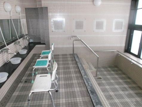 長方形の水の入っていない浴槽が右手に。シャワースペースには鏡が付いていて、背もたれ付きのシャワーチェアも設置されている。