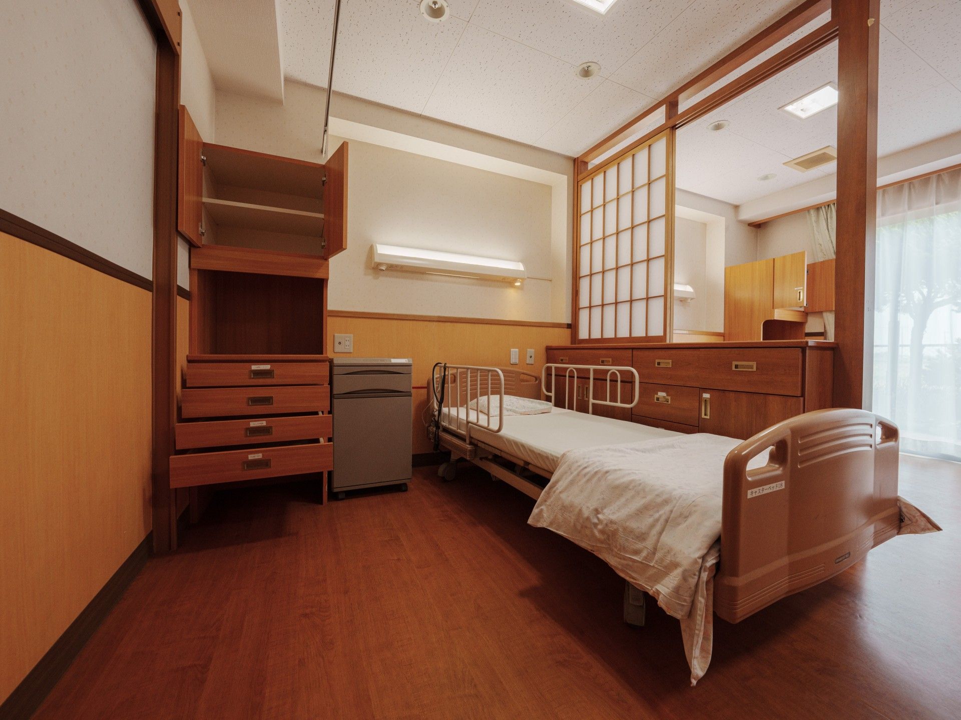 車椅子に座っている高齢女性の隣りに寄り添う男性ヘルパー