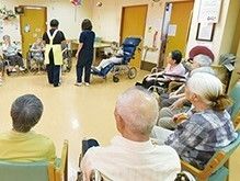 手すりにつかまり車に乗る高齢男性と介助をするヘルパー