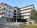 大きなマンションのような白を基調とした建物。玄関先には車寄せが付き、各フロアにベランダもある。