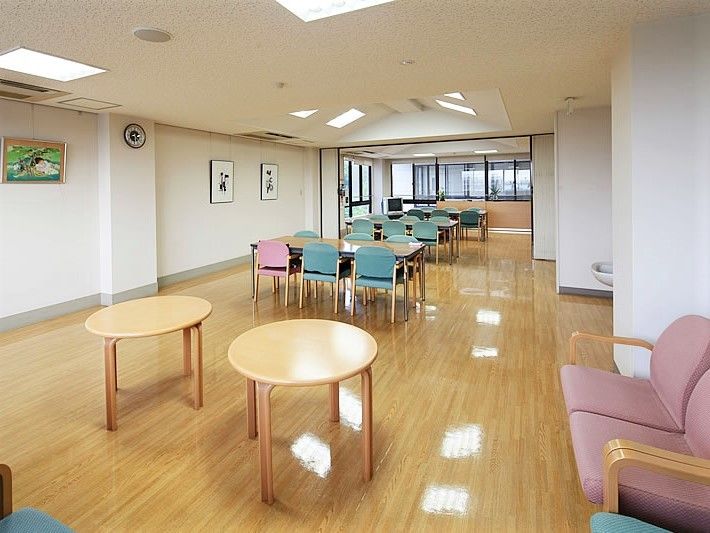 ピンクとグリーンの椅子がセットされたダイニングテーブルが置くに並び、手前には歓談スペースが設けられている。
