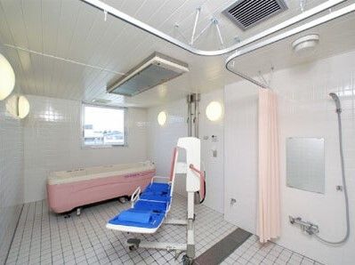 寝たまま入浴可能な寝台浴が設置された浴室。タイル張りでシャワースペースもある。