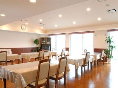 大きな窓がたくさん付いた共有スペース。テーブルクロスがセットされたテーブルが複数ある。