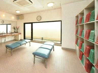 脱衣所の中央にはブルーのベンチが二つ置かれ、棚には赤や緑の家具が並べられている。