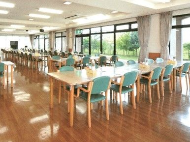 壁一面が窓となっている開放的な食堂。テーブルが複数並び、テレビもある。