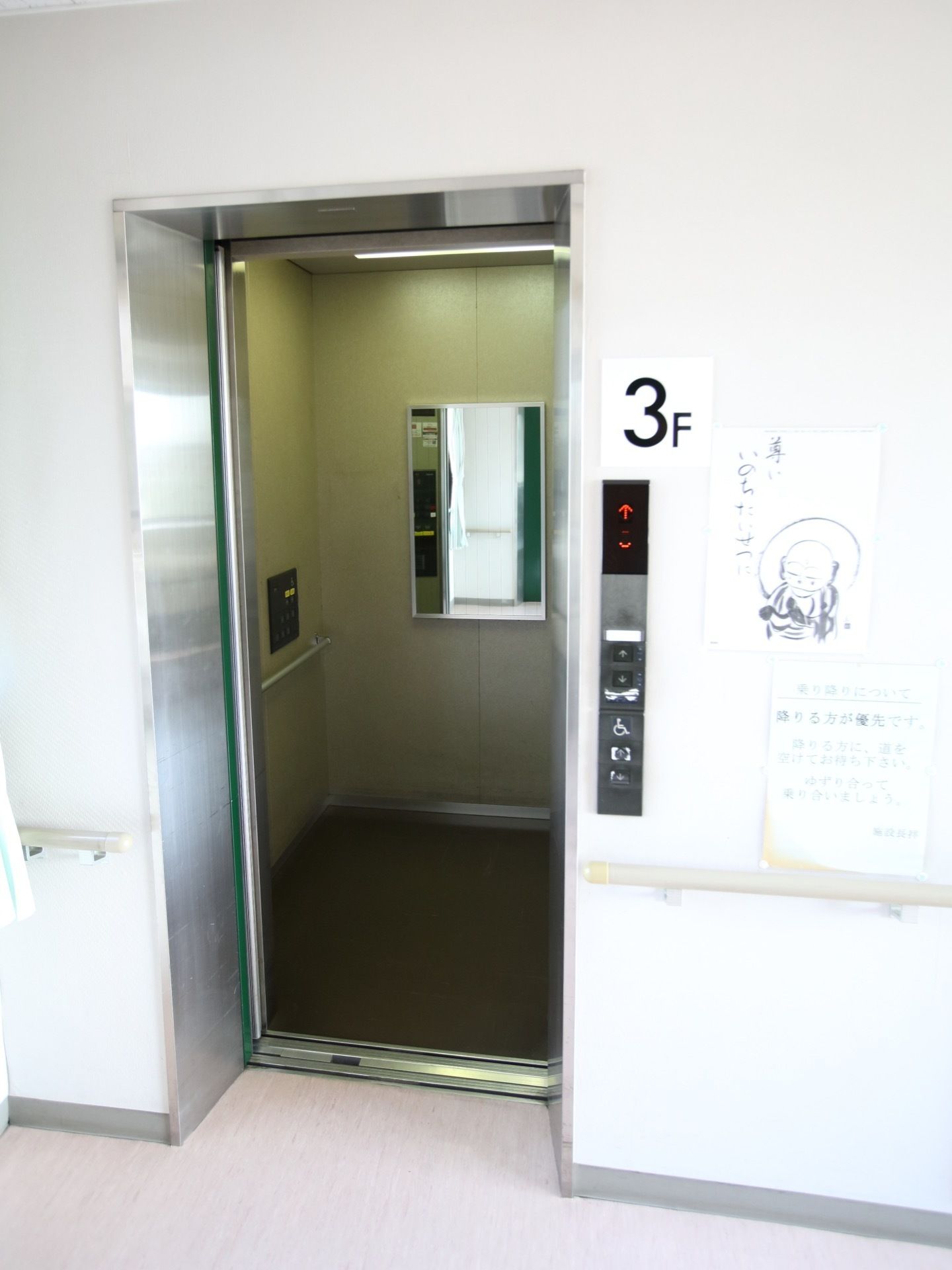 エレベーターの中には鏡や手すり、操作ボタンがある。外側の壁には階数が書かれたプレートが付けられている。