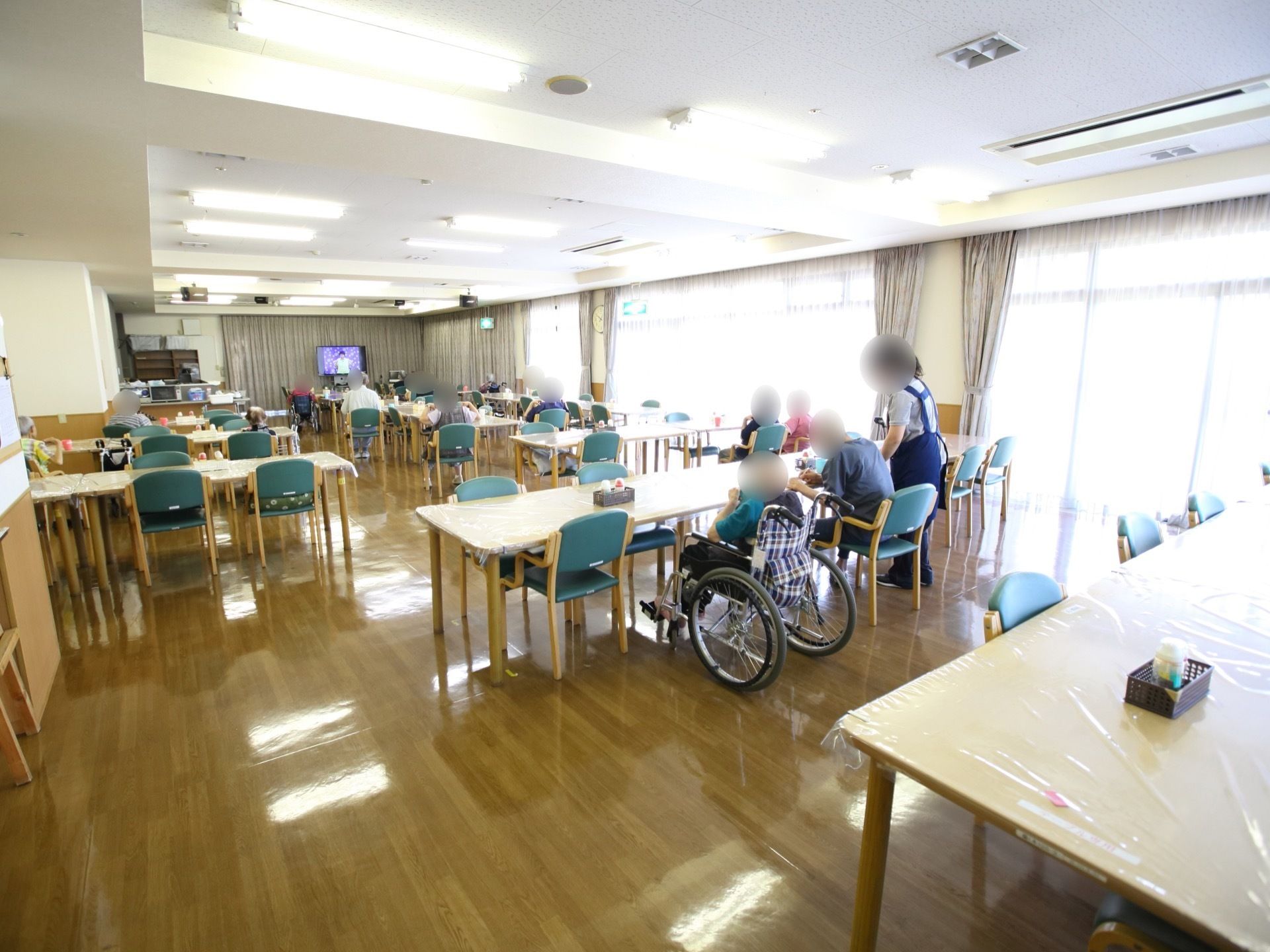 食堂は明るくて広々としており、テーブルと椅子がたくさん設置されている。車椅子に乗ったままで席に着けるようになっている。