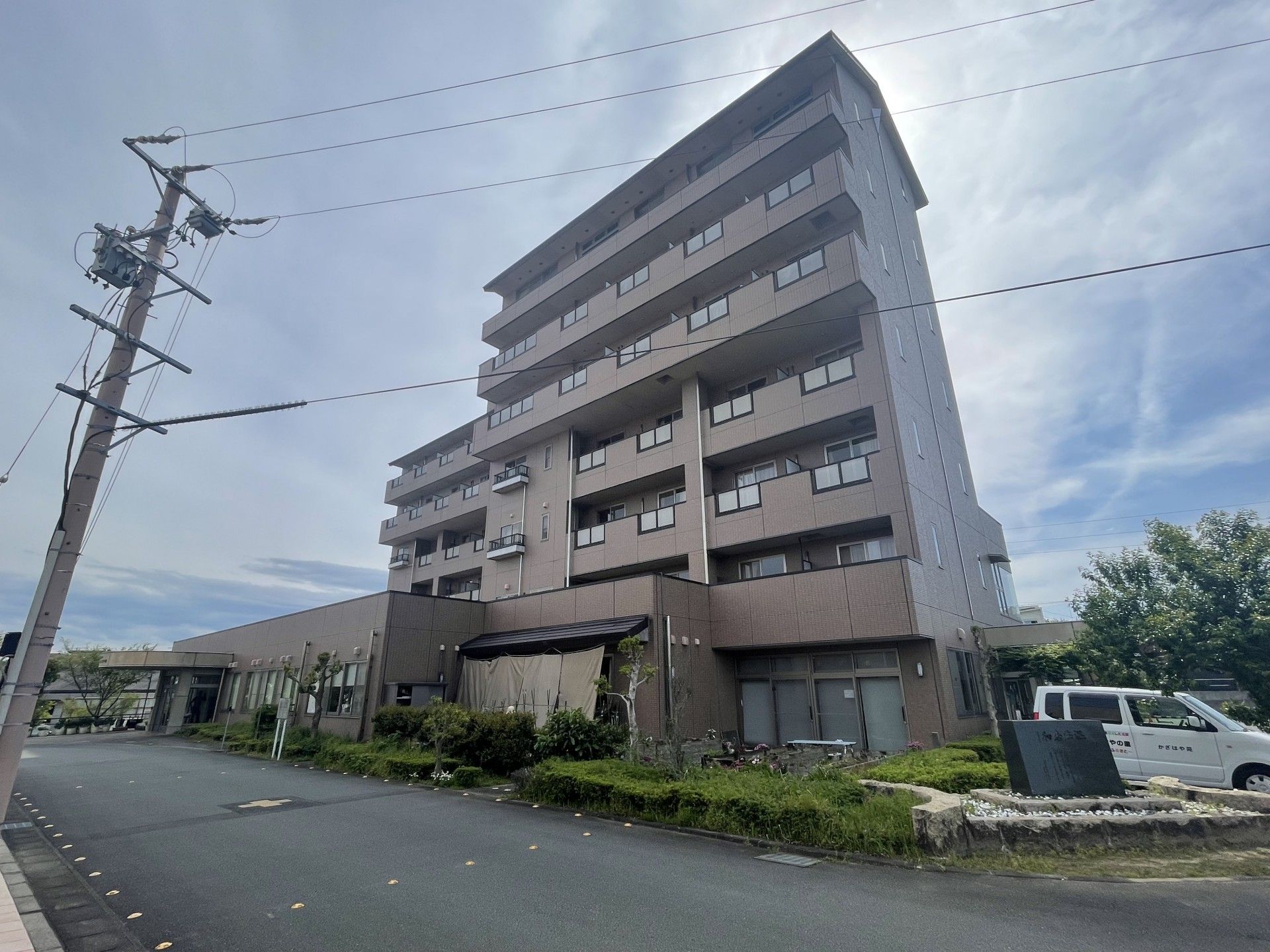 寝具付きのベッドが設置されたフローリングの居室には、エアコンや収納棚、大きな窓もあり、ベランダも付いている。