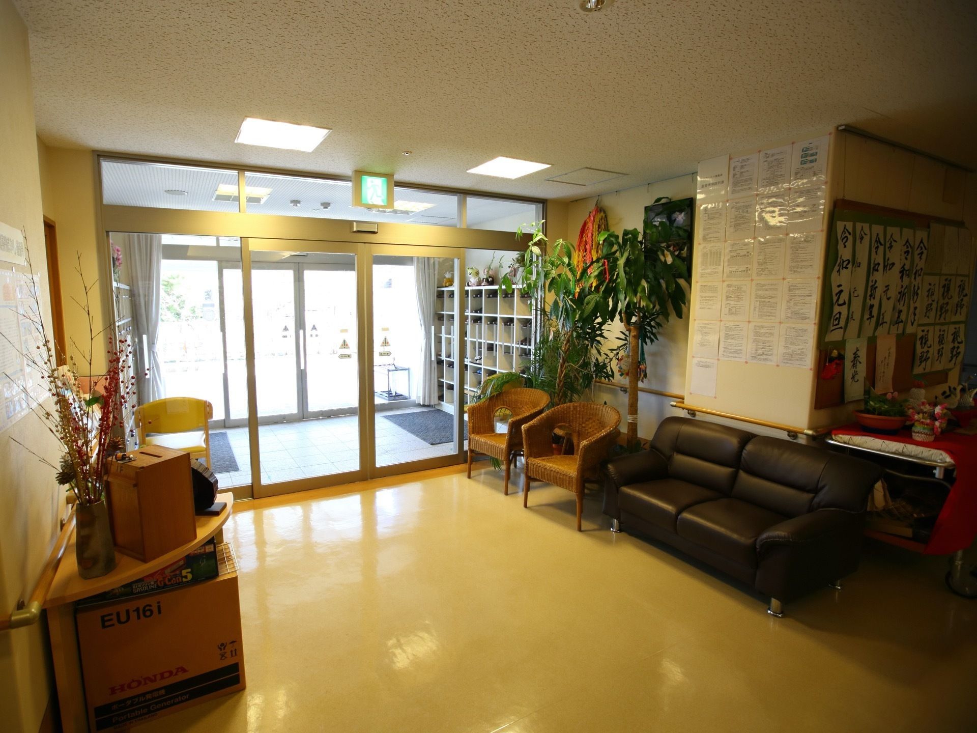 玄関は2重の自動扉になっている。フロアにはソファーや観葉植物があり、壁に入居者様の書いた習字が飾ってある。