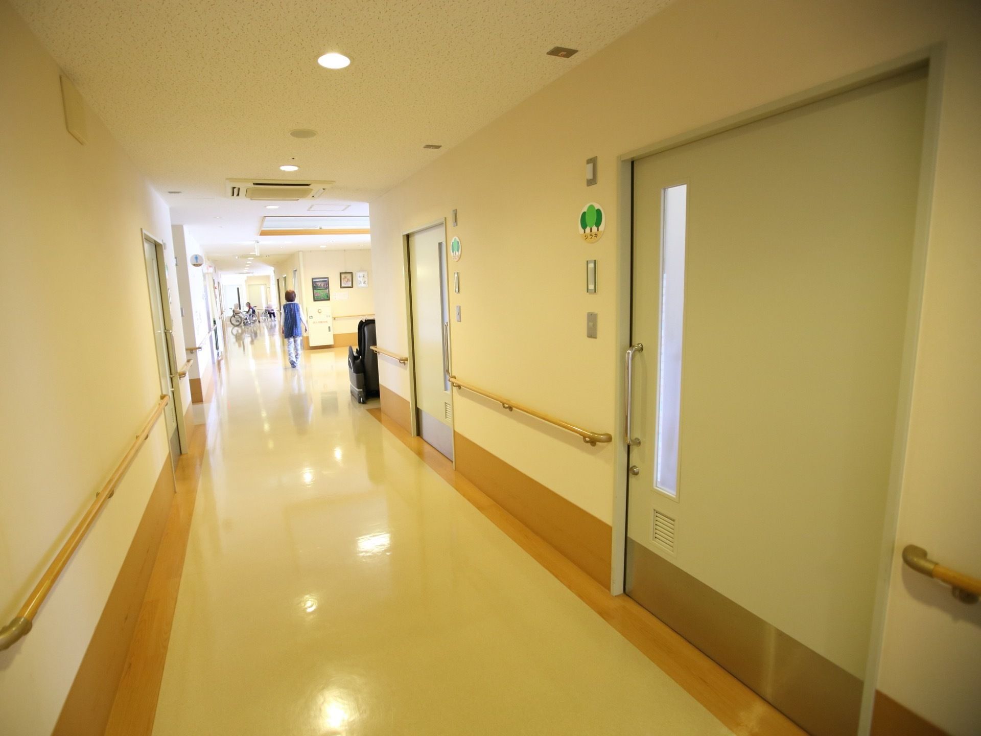 明るい通路が真っすぐ伸びている。両サイドには居室が並んでいて、大きな引き戸の扉になっている。壁には手すりが付いている。