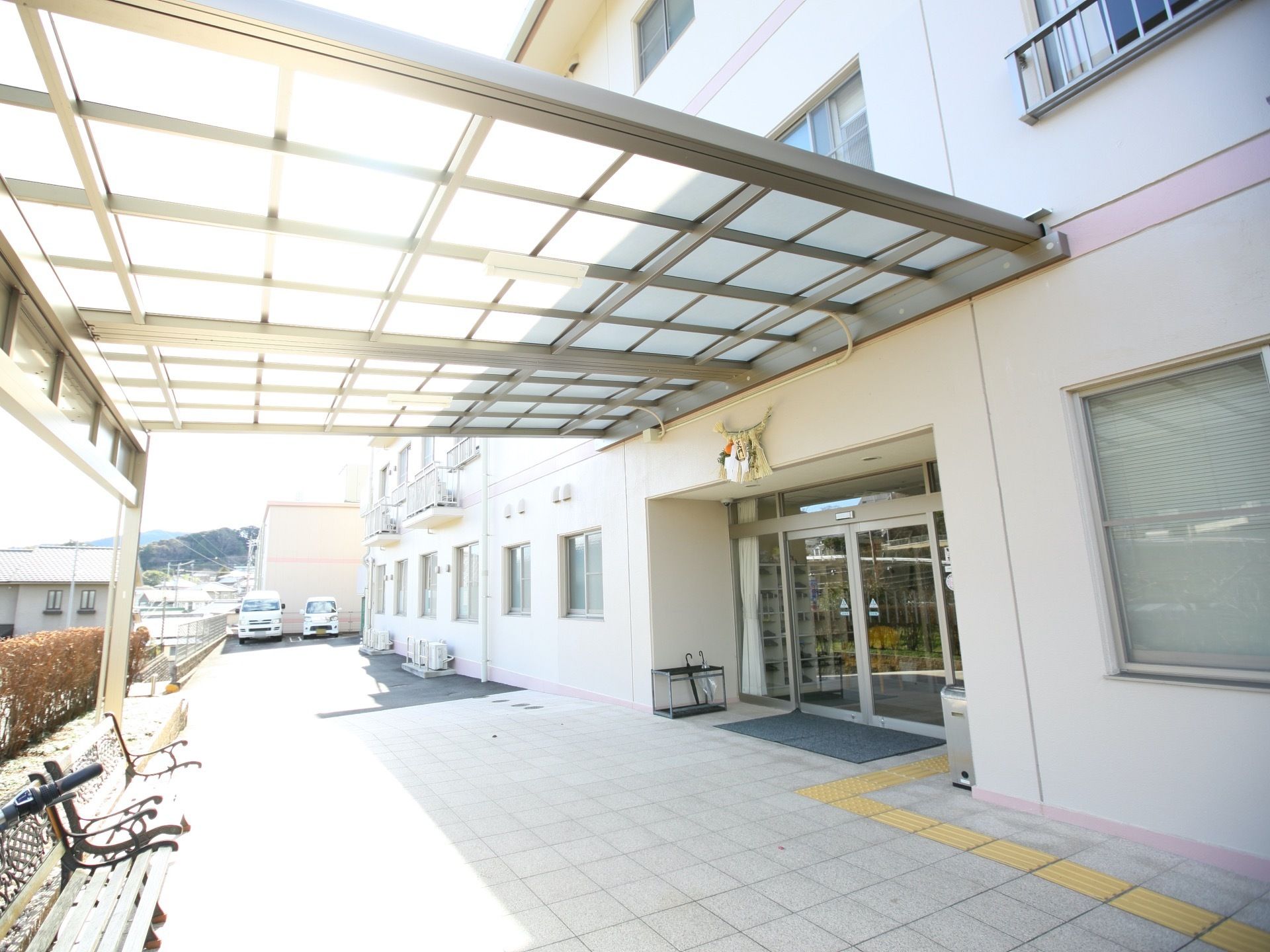 玄関前には陽が良く当たり、屋根の下にベンチが置いてある。車寄せも広く雨にぬれずに車への乗降が出来る。