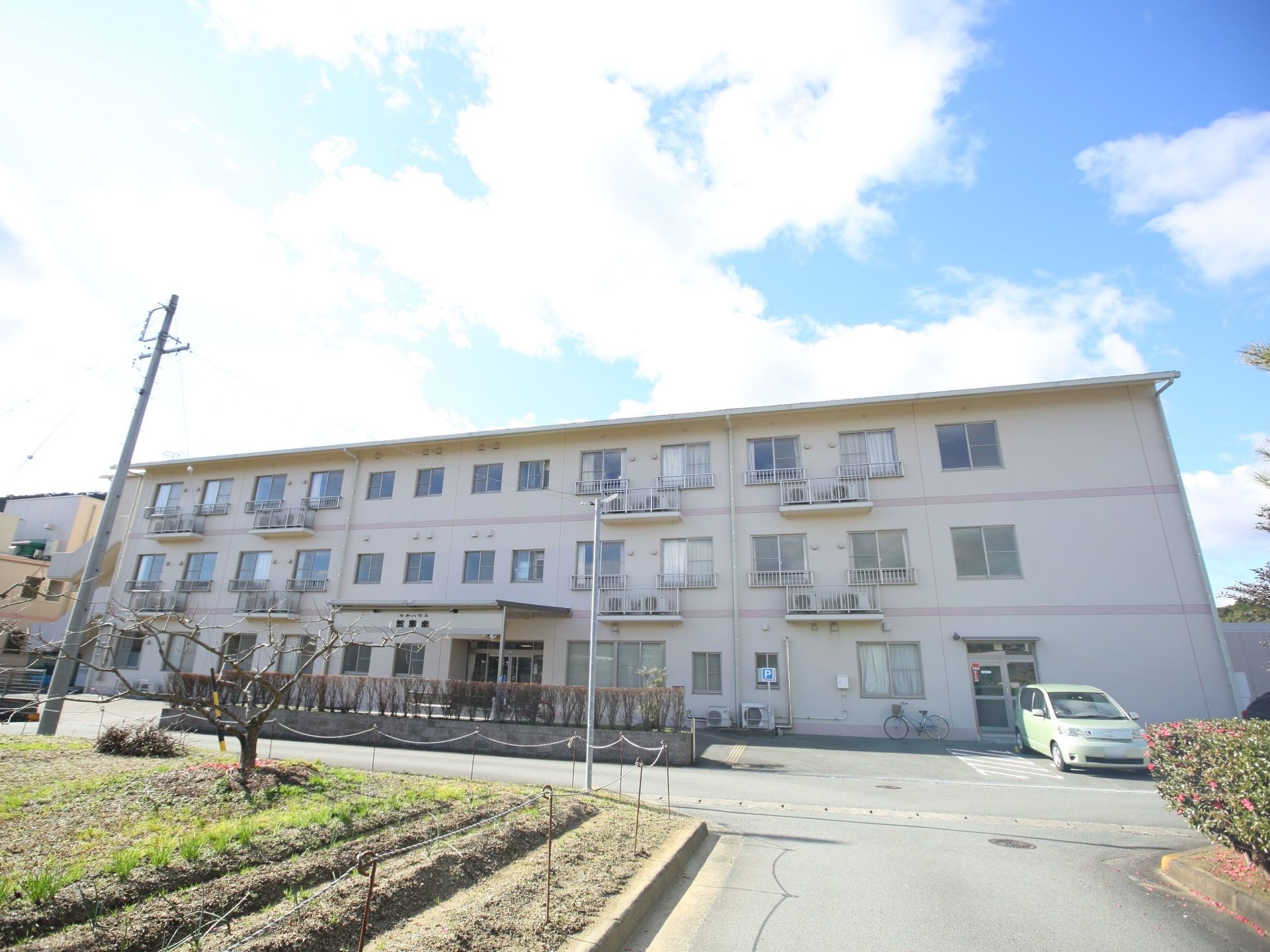 3階建ての施設前は背丈の低い木と畑になっている。居室の窓から眺めると、開放感があって、季節を感じることができる。