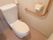 居室のトイレに白い洋式便器があり、後ろの棚には替えのペーパーが置いてある。ペーパーホルダーをＬ字に囲むように手すりが設置されている。