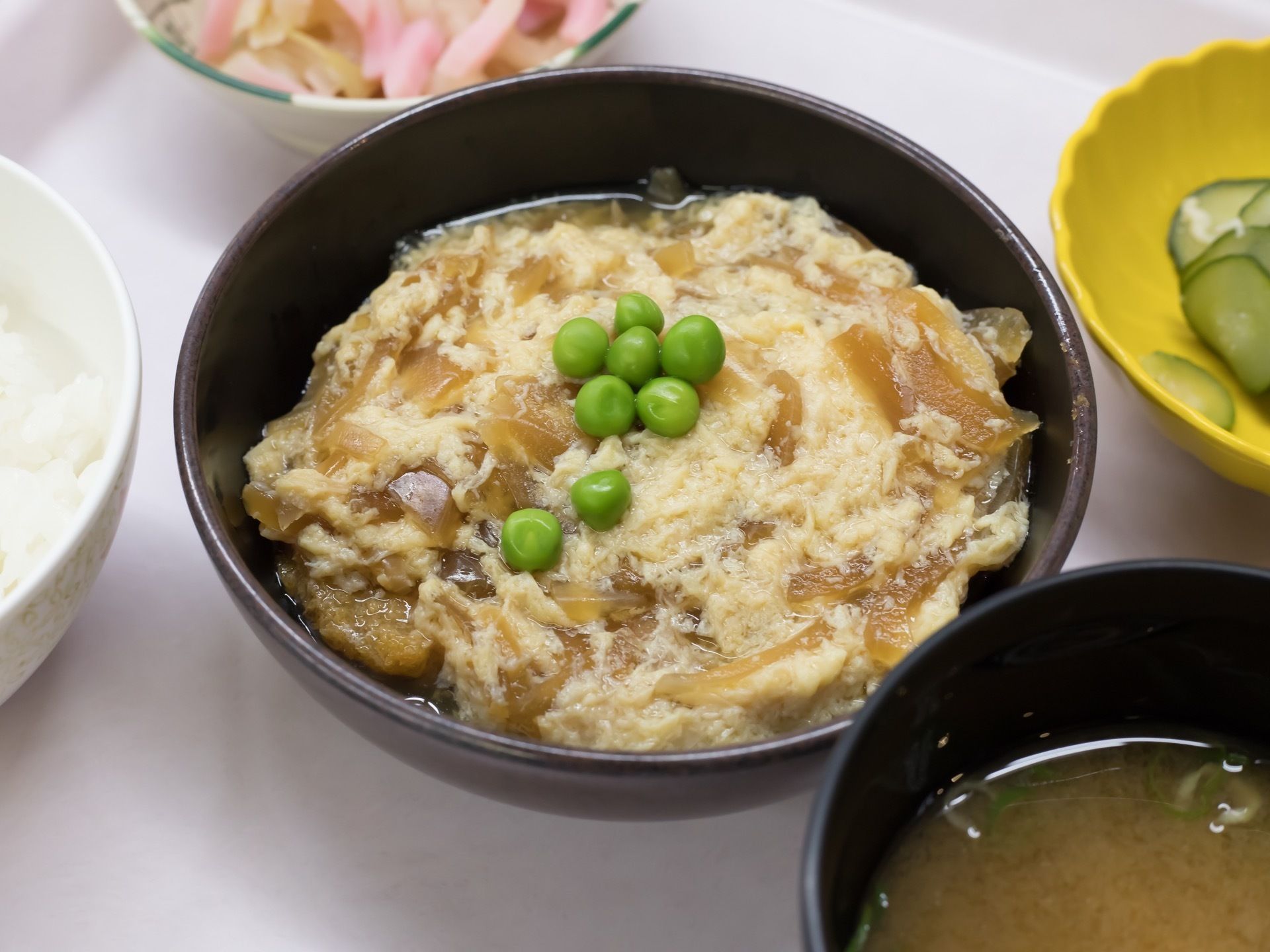 ご飯やみそ汁の他、グリーンピースが乗った卵とじなど、それぞれお茶碗やお皿に盛りつけられて、トレイに置かれている。