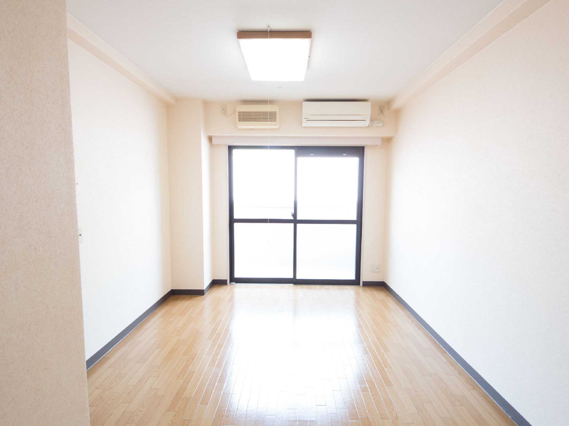 鉄筋コンクリート造りの３階建ての建物。淡いベージュでやさしい印象。建物周辺には花や木が植えられている。