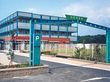 白を基調とした建物にはブルーのラインが入り、ベランダが設置され、周辺にはフェンスがあり、日当たりのいい場所にある。
