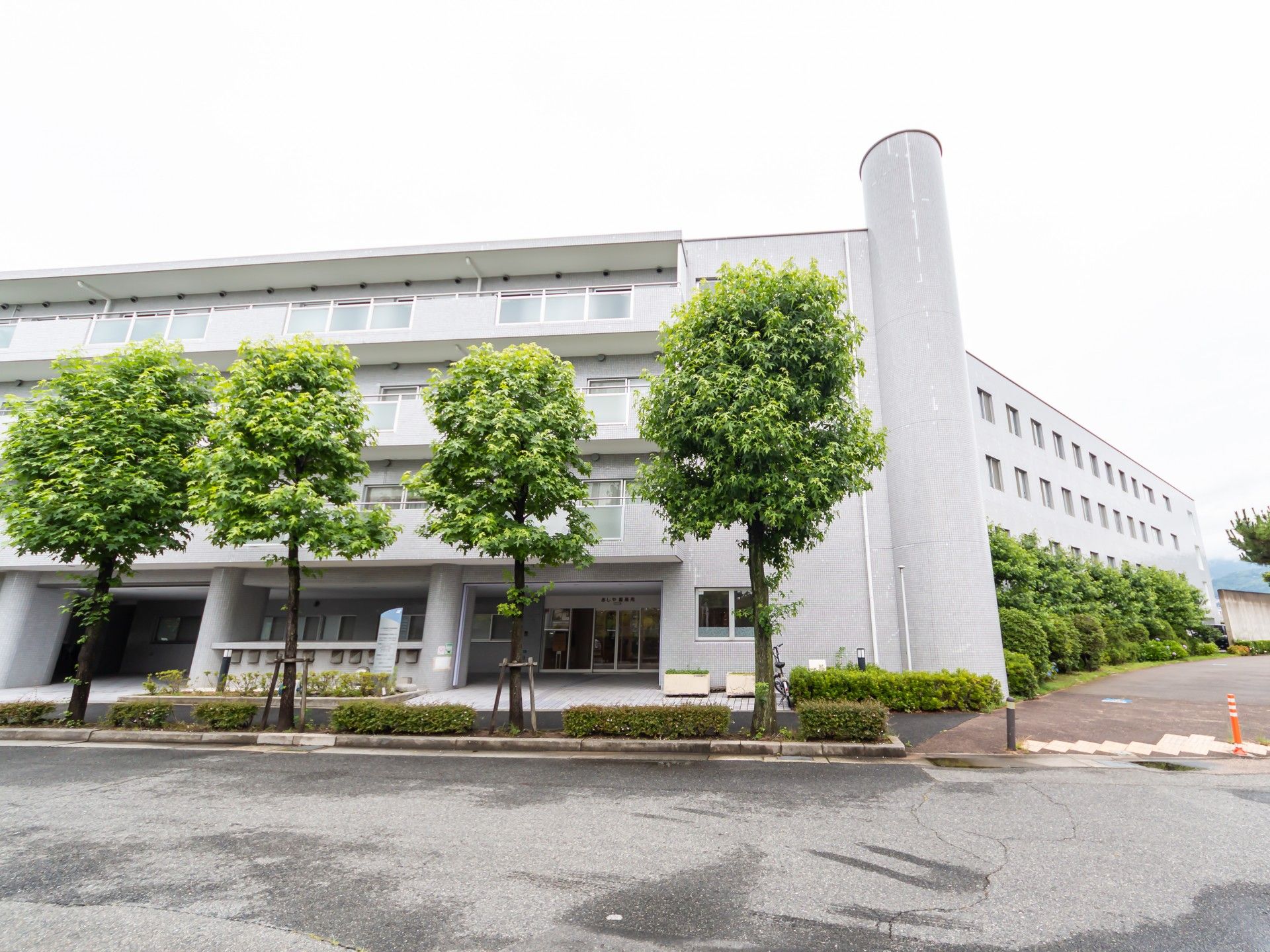 笑顔で高齢男性の介助に当たるボーダー柄のエプロンを付けた女性スタッフ。