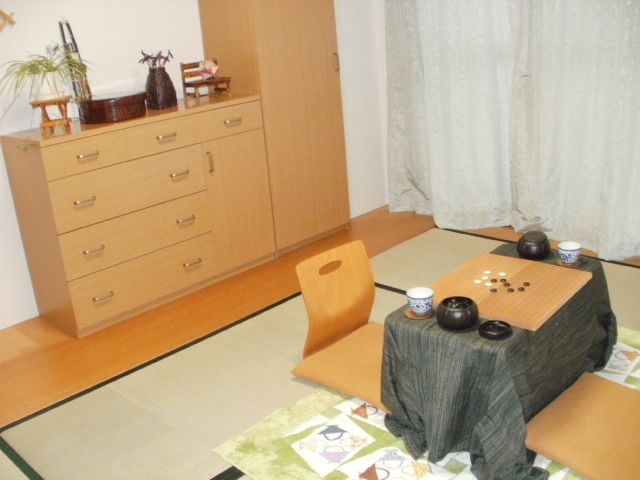 収納家具の上には小物が飾られ、テーブルにはグレーのクロスがかけられ囲碁セットが置かれている。