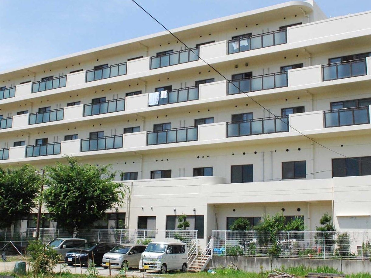 横に長い大きな建物は白を基調としていて清潔感がある。建物の周辺には緑も多い。