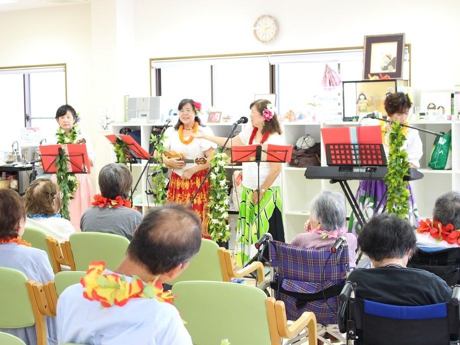 四人の女性が歌を歌う催し物で集まり、椅子に座る入居者たち